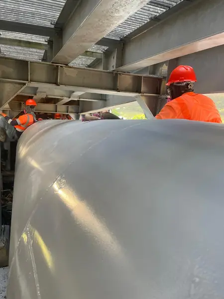 Cuadrilla con casco aplicando recubrimiento a una tubería industrial de gran diámetro