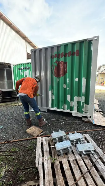 Técnico preparando la superficie de un contenedor para pintura industrial