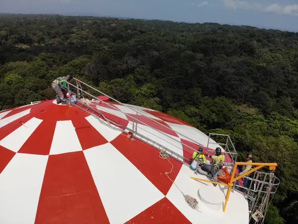 Pintura en rojo y blanco del techo de un tanque con trabajo en altura