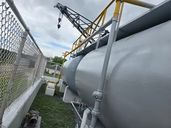 Tanque horizontal recubierto junto a una grúa en planta industrial